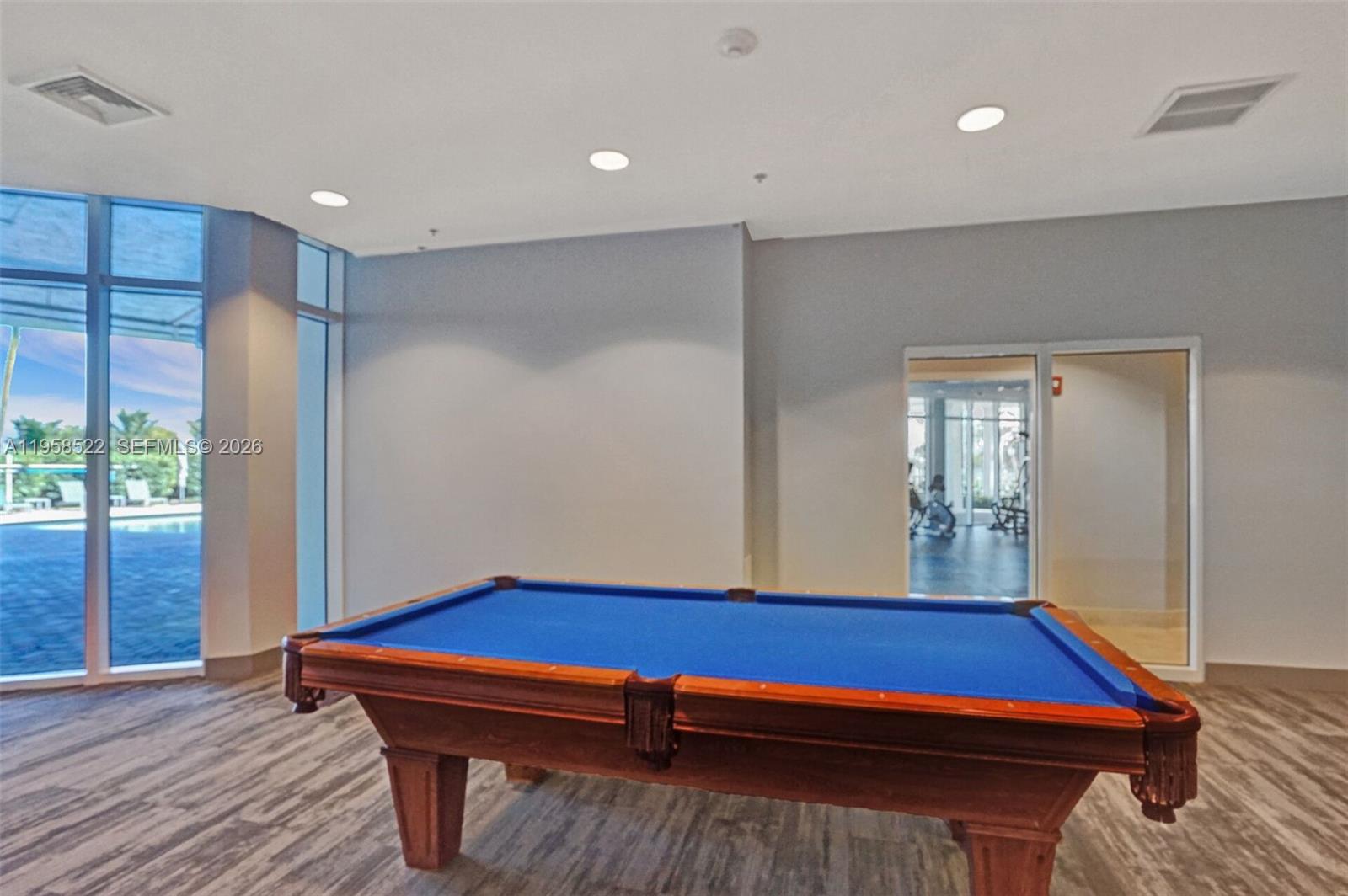 A room with a blue pool table, wood-look flooring, and floor-to-ceiling windows — 6515 Collins Ave # 901, Miami Beach FL 33141, MIAMI BEACH, FL