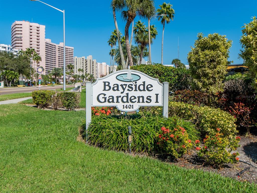 A sign for Bayside Gardens I stands in a grassy area with palm trees behind — 1401 GULF BOULEVARD UNIT 215, CLEARWATER BEACH, FL