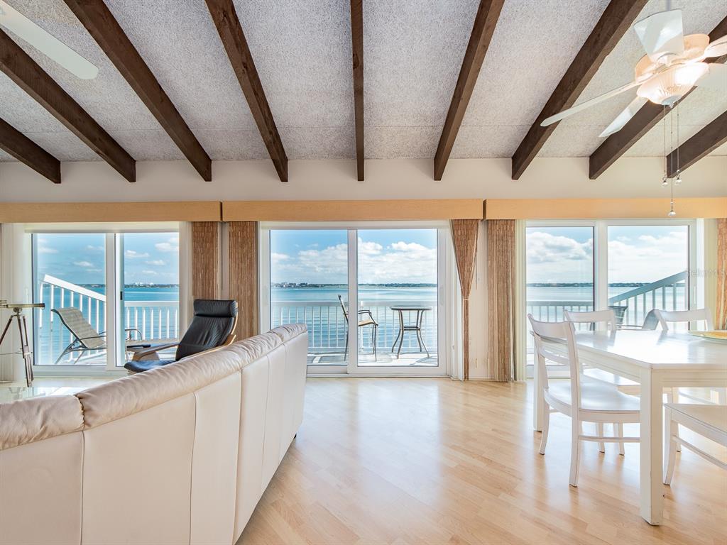 A living and dining area features vaulted wood-beamed ceilings, light wood floors, and waterfront views — 1401 GULF BOULEVARD UNIT 215, CLEARWATER BEACH, FL