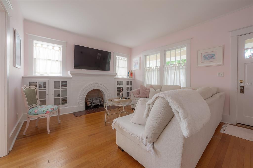 A living room with light pink walls, hardwood floors, a white fireplace, and a white sofa — 2808 W AQUILLA STREET, TAMPA, FL