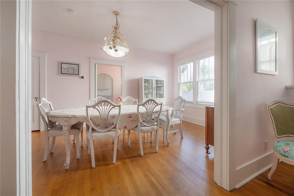 A dining room with light pink walls, hardwood floors, and a white wooden table set — 2808 W AQUILLA STREET, TAMPA, FL