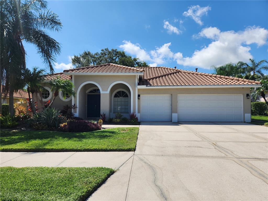 A single-story house with a tile roof, two garage doors, and a landscaped front yard — 5274 FAR OAK CIRCLE, SARASOTA, FL