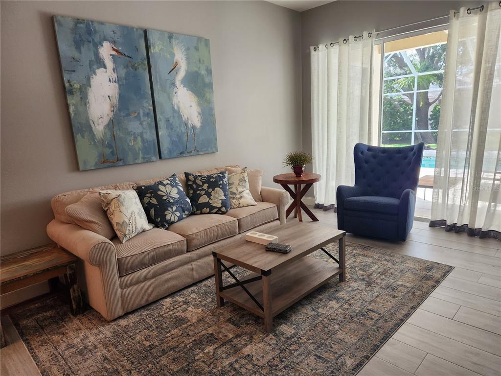 A living room features a beige sofa, a blue armchair, and a coffee table — 5274 FAR OAK CIRCLE, SARASOTA, FL