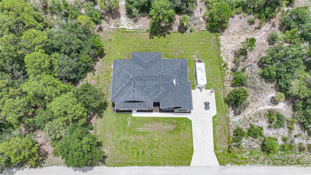 An aerial view shows a house with a dark roof, a driveway, and surrounding trees — 13190 BANYAN DRIVE, PUNTA GORDA, FL
