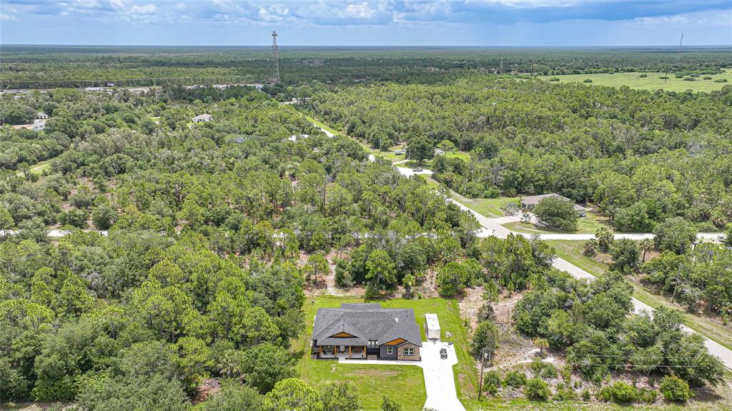 An aerial view shows a single-story house with a dark roof surrounded by dense forest — 13190 BANYAN DRIVE, PUNTA GORDA, FL