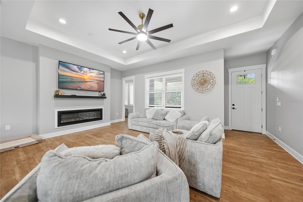 A living room features a tray ceiling, ceiling fan, fireplace, and light-colored furniture — 13190 BANYAN DRIVE, PUNTA GORDA, FL