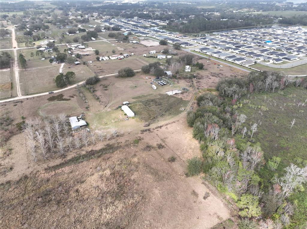 An aerial view shows a rural property with several buildings adjacent to a residential subdivision — 307 & 317 SKYBLUE LANE, AUBURNDALE, FL