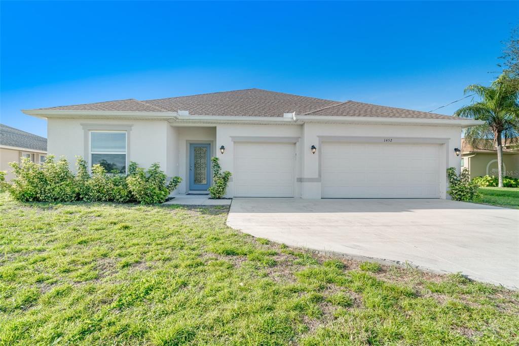 A single-story house with a light-colored stucco exterior, a three-car garage, and a blue door — 1452 SE 13TH TERRACE, CAPE CORAL, FL