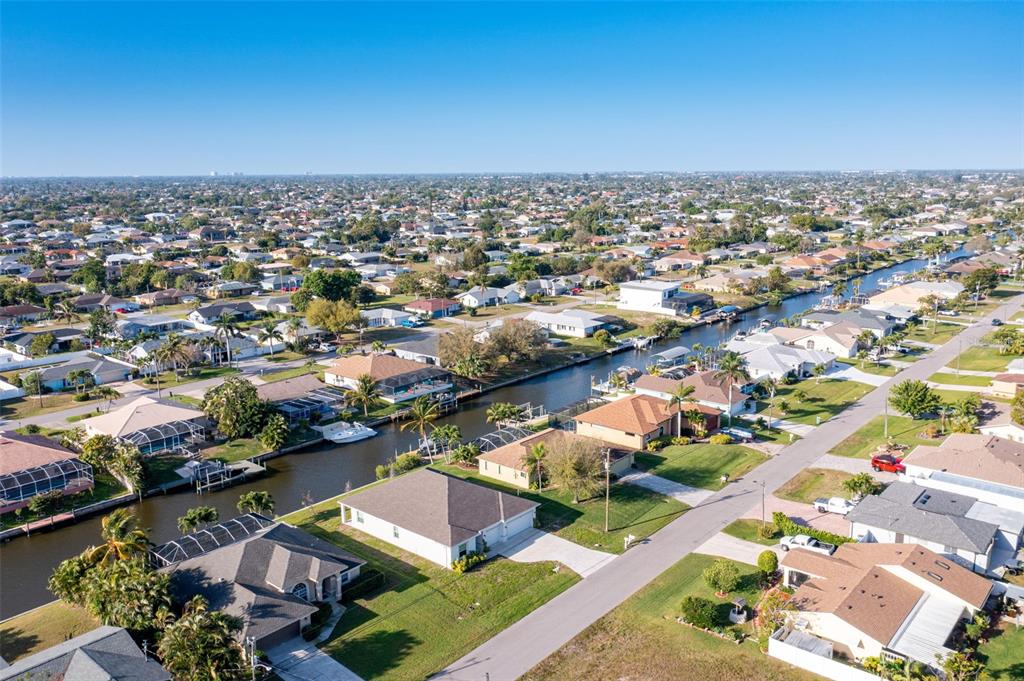 An aerial view shows residential houses along a canal in a suburban neighborhood — 1452 SE 13TH TERRACE, CAPE CORAL, FL