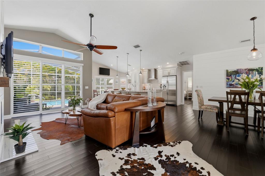 A living and dining area features dark wood floors, a cowhide rug, and double glass doors — 631 DE SOTO DRIVE, TIERRA VERDE, FL