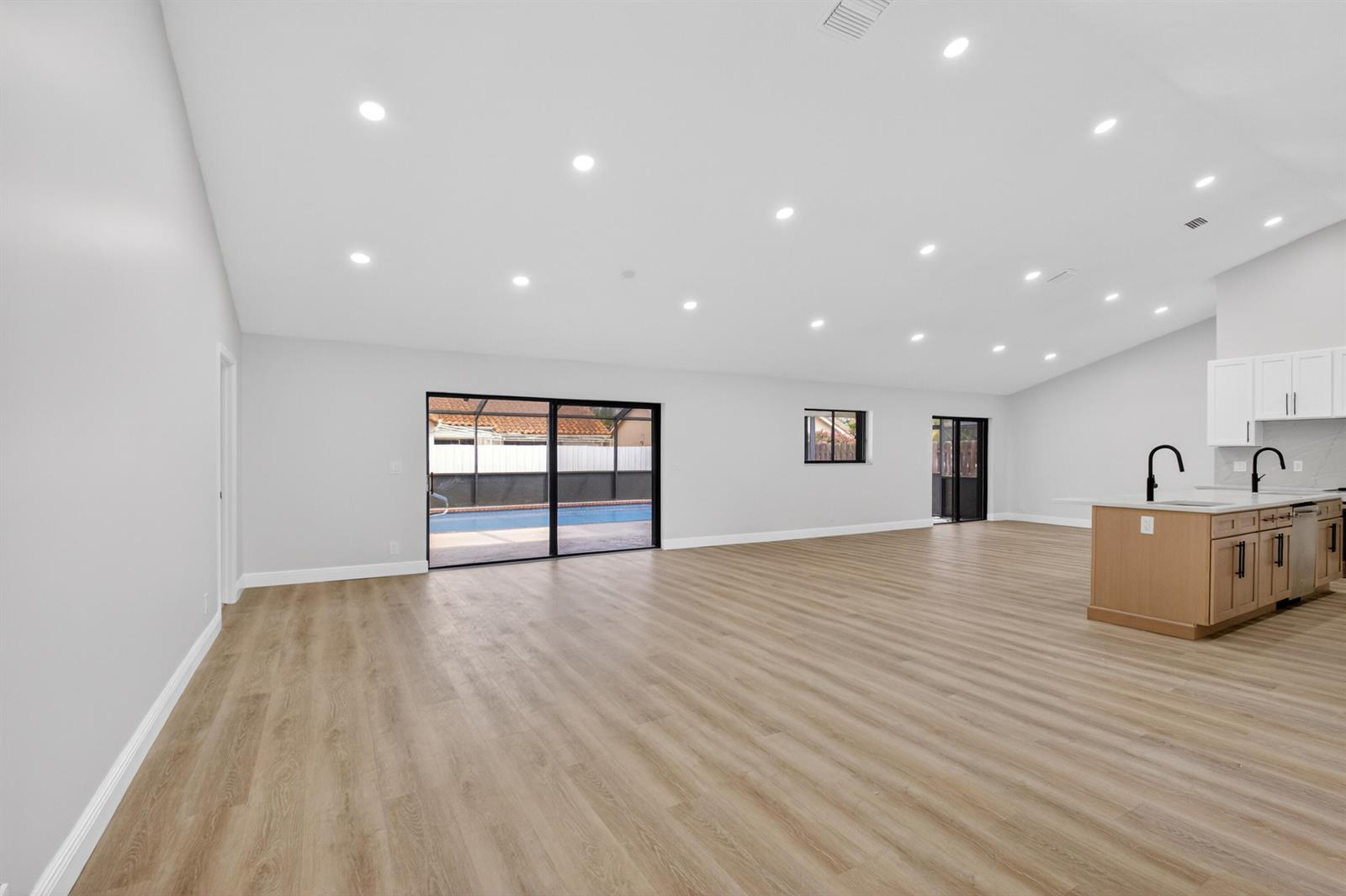 An open-concept living area features light wood-look flooring, recessed lighting, and a kitchen island — 9362 Laurel Green Drive, Boynton Beach FL 33437, BOYNTON BEACH, FL