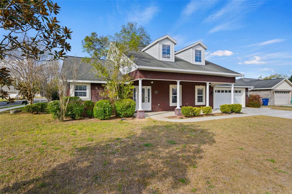 A two-story brick house with a front porch, dormer windows, and an attached garage — 25178 SW 20TH AVENUE, NEWBERRY, FL