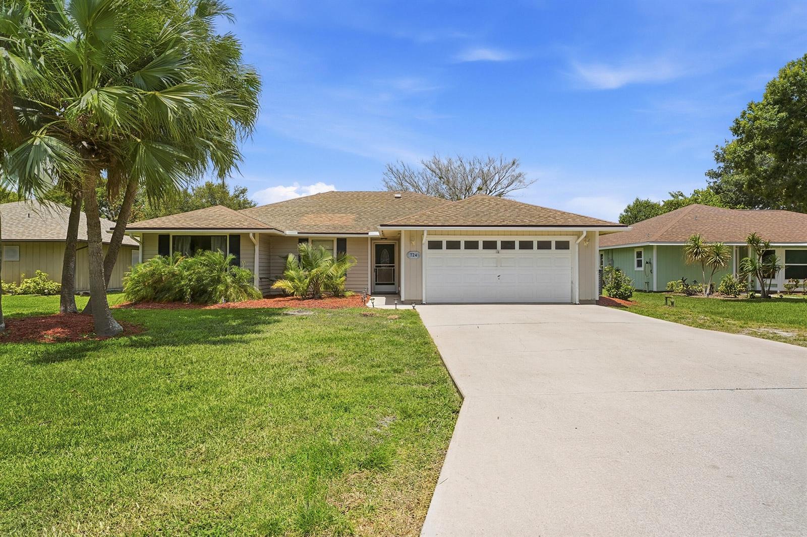 A single-story house with a beige exterior, a white garage door, and a palm tree — 724 24th Square, Vero Beach FL 32962, VERO BEACH, FL