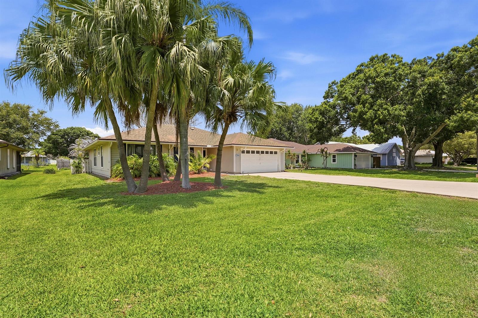 A single-story house with a white garage door, palm trees, and a large front lawn — 724 24th Square, Vero Beach FL 32962, VERO BEACH, FL