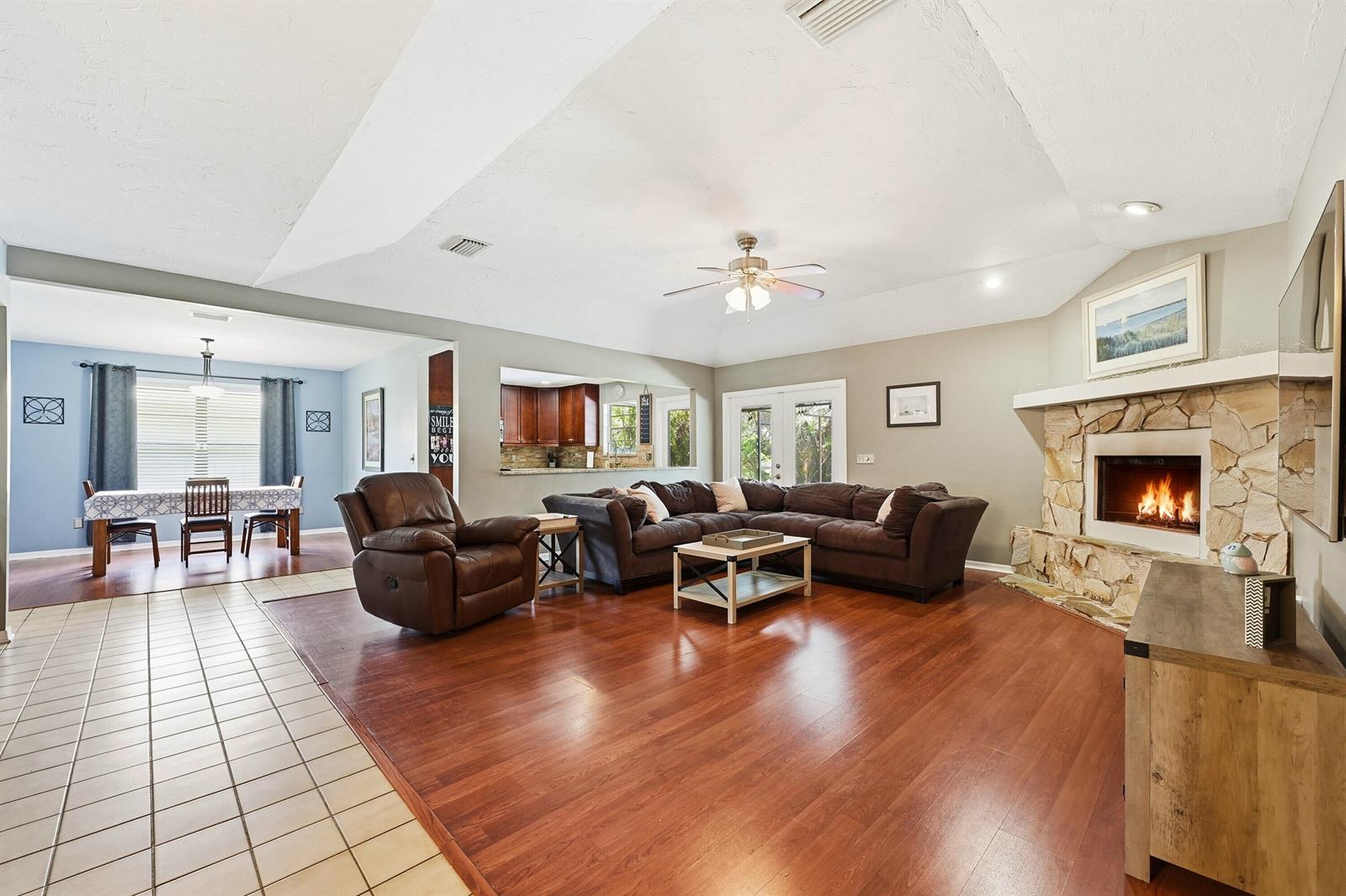 A living room with hardwood floors, a stone fireplace, and an adjacent dining area — 724 24th Square, Vero Beach FL 32962, VERO BEACH, FL