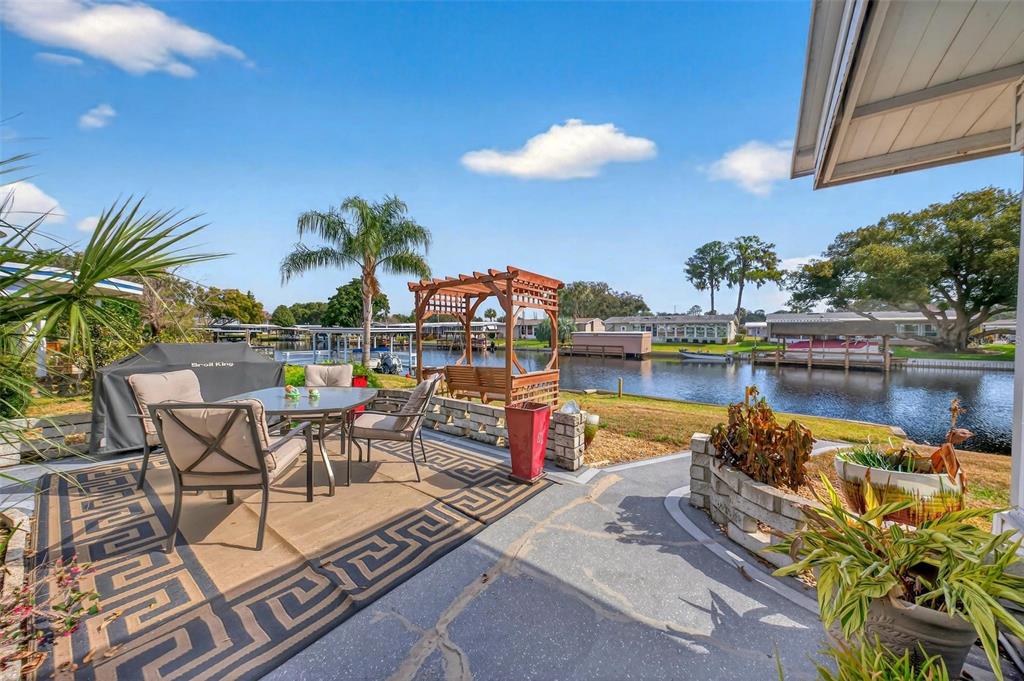 A patio with outdoor furniture and a wooden pergola overlooks a canal with boat docks — 1018 SOUTHLAND DRIVE, TAVARES, FL