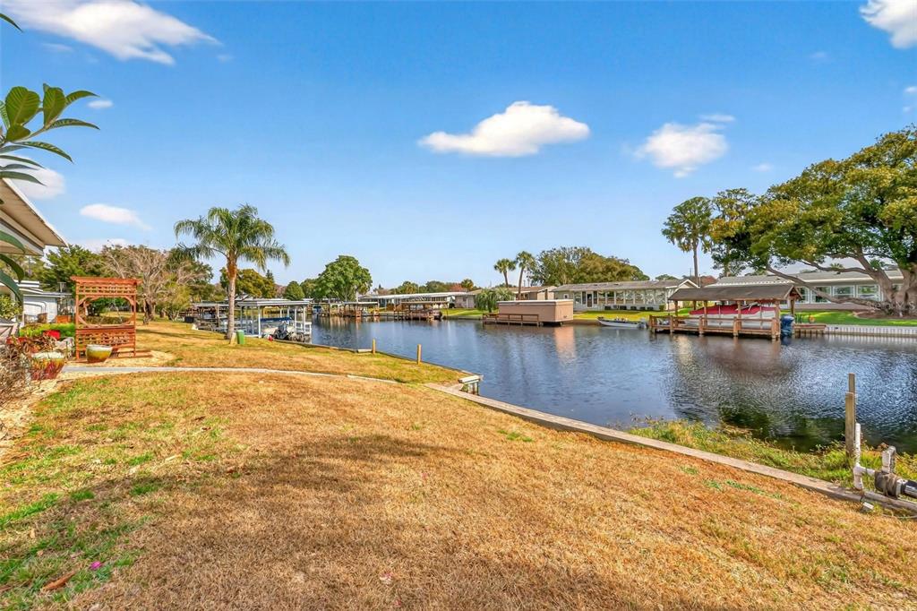 A grassy backyard leads to a canal with several boat docks and covered slips — 1018 SOUTHLAND DRIVE, TAVARES, FL