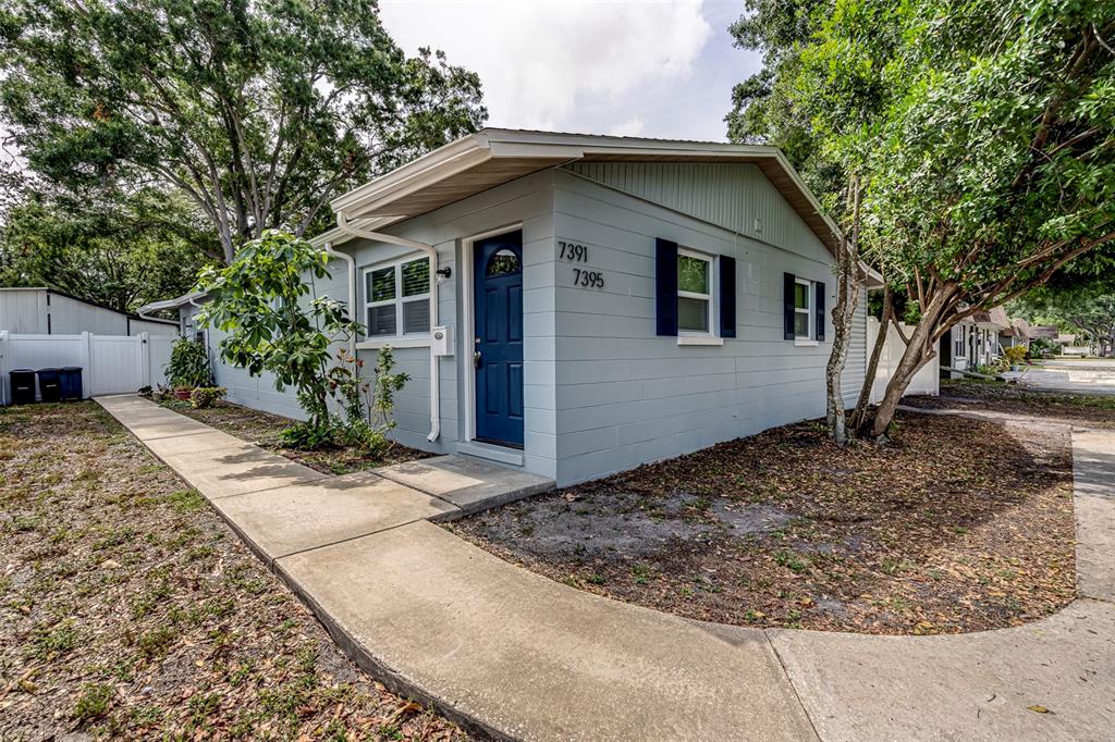 A light blue, single-story concrete block house with a blue front door and sidewalk — 7391 34TH STREET N, PINELLAS PARK, FL