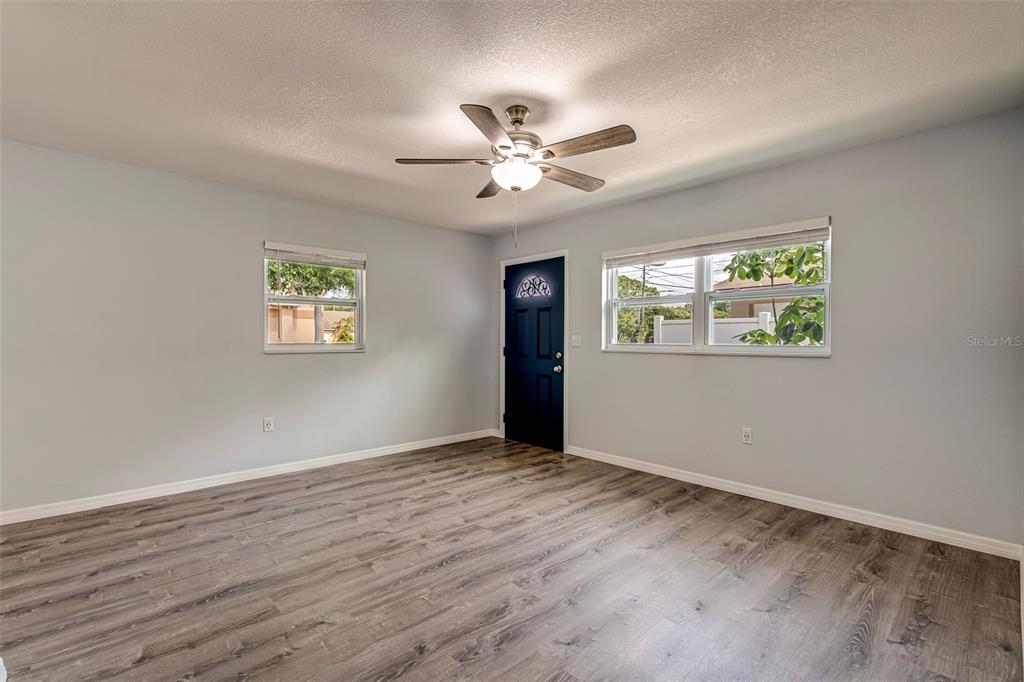 A room with light gray walls, wood-look flooring, a ceiling fan, and a dark door — 7391 34TH STREET N, PINELLAS PARK, FL