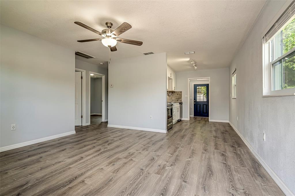 An open-concept living area features light gray walls, wood-look flooring, and a ceiling fan — 7391 34TH STREET N, PINELLAS PARK, FL