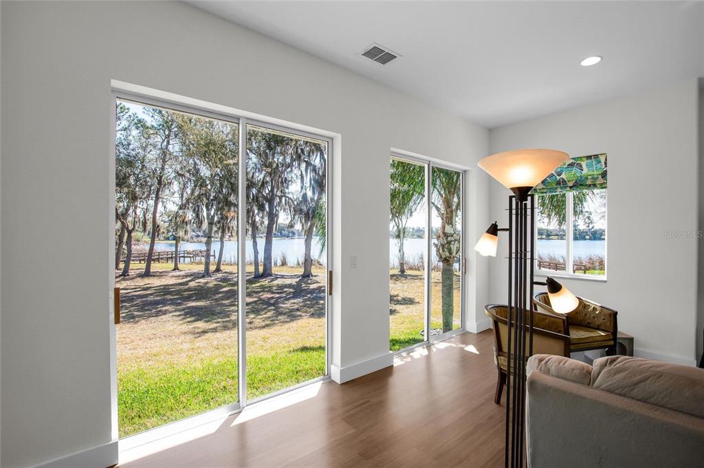 A living area features wood floors, sliding glass doors, and a view of a lake — 381 NOLANE LANE, POLK CITY, FL
