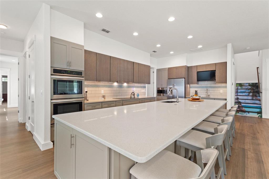 A modern kitchen features a large white quartz island, gray cabinetry, and stainless steel appliances — 381 NOLANE LANE, POLK CITY, FL