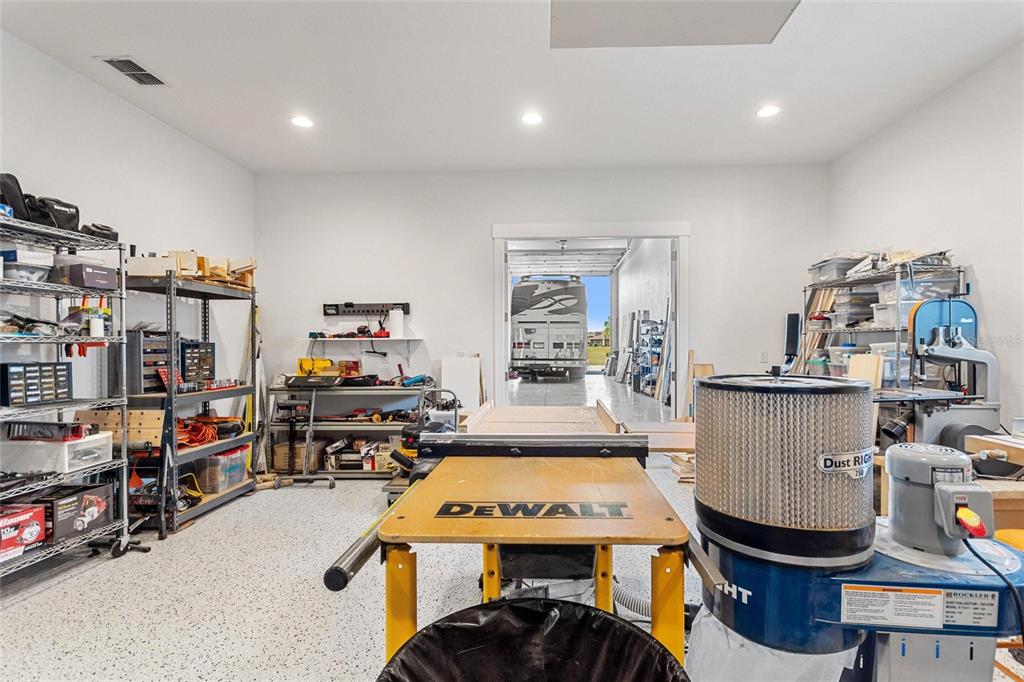 A garage workshop features a DeWalt table saw, a dust collector, and metal shelving units — 381 NOLANE LANE, POLK CITY, FL