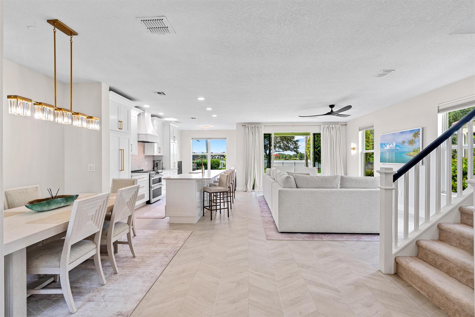 An open-concept living area features a kitchen, dining space, and stairs with herringbone flooring — 1570 NW 48th Place, Boca Raton FL 33431, BOCA RATON, FL