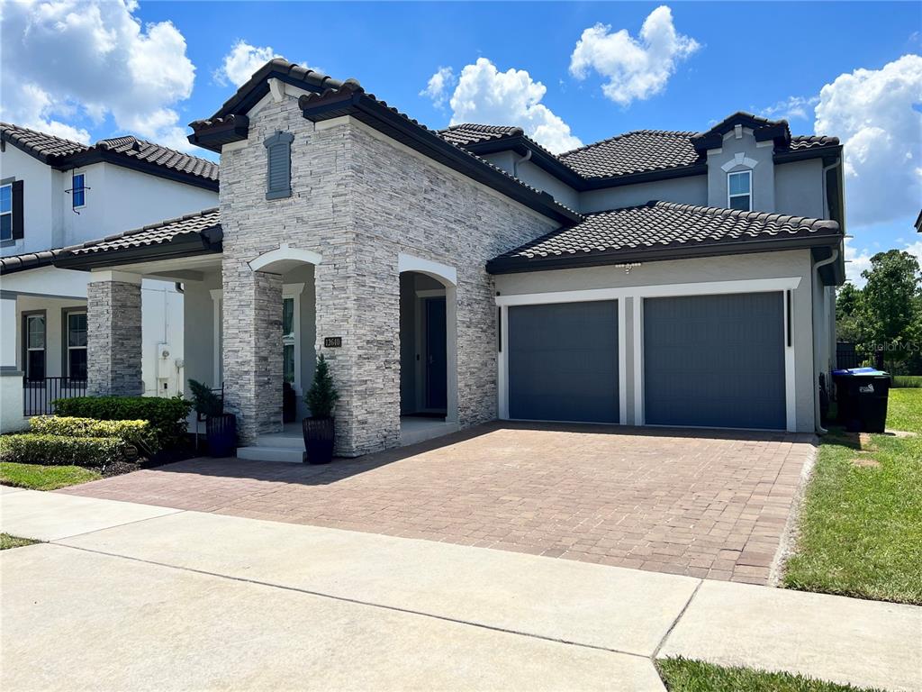 A two-story house features a stone facade, a tiled roof, and a two-car garage — 12640 SALOMON COVE DRIVE, WINDERMERE, FL