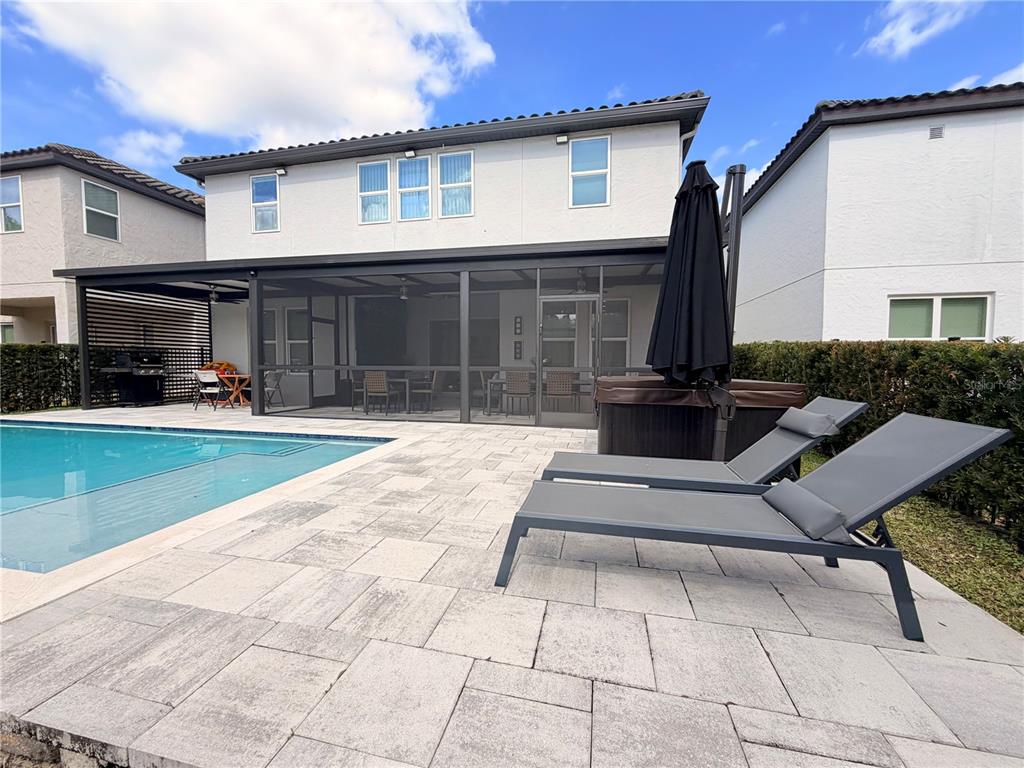 A backyard features a swimming pool, a screened-in patio, and two lounge chairs on pavers — 12640 SALOMON COVE DRIVE, WINDERMERE, FL