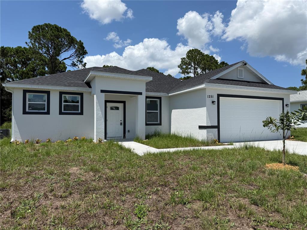 A single-story house with white stucco walls, dark trim, and a two-car garage — 1251 SCOTTISH STREET SW, PALM BAY, FL