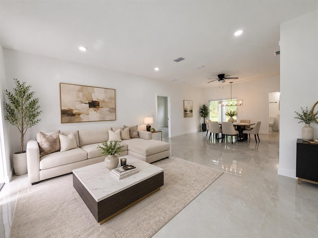 A bright, open-concept living and dining area features neutral furniture, tile floors, and recessed lighting — 1251 SCOTTISH STREET SW, PALM BAY, FL