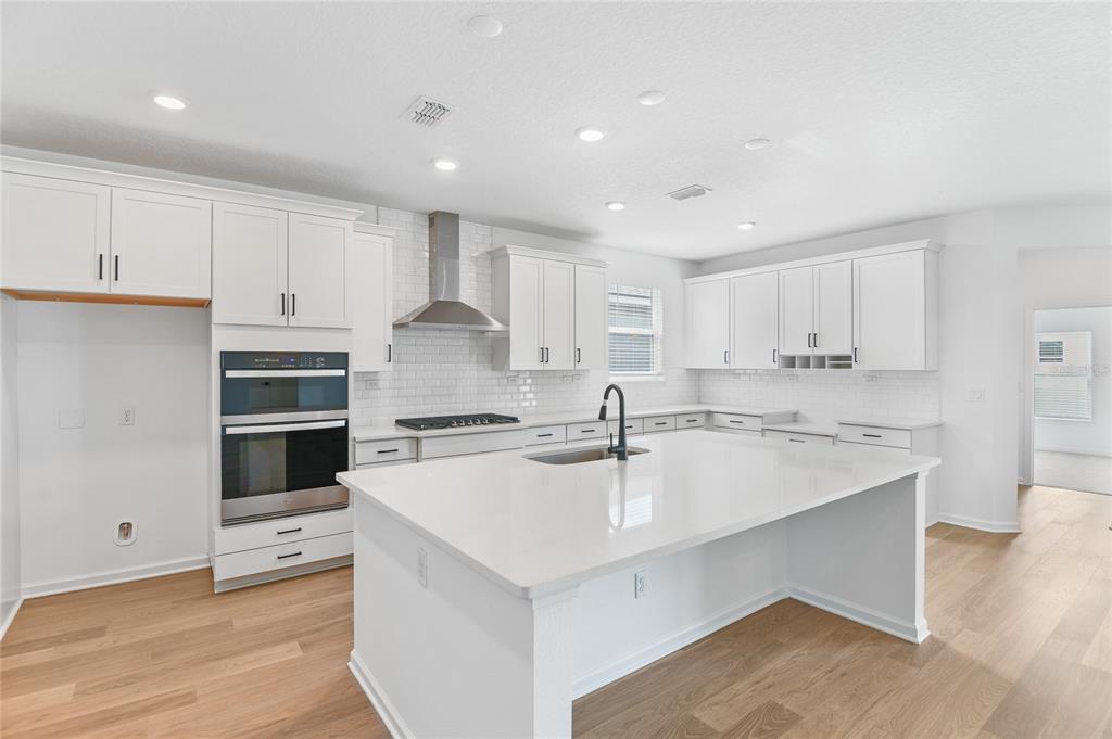 A bright kitchen features white cabinets, a large quartz island, and stainless steel appliances — 34 WINDMILL PALM WAY, PALM COAST, FL