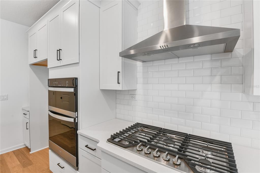 A modern kitchen features white cabinets, a stainless steel double oven, and a gas cooktop — 34 WINDMILL PALM WAY, PALM COAST, FL