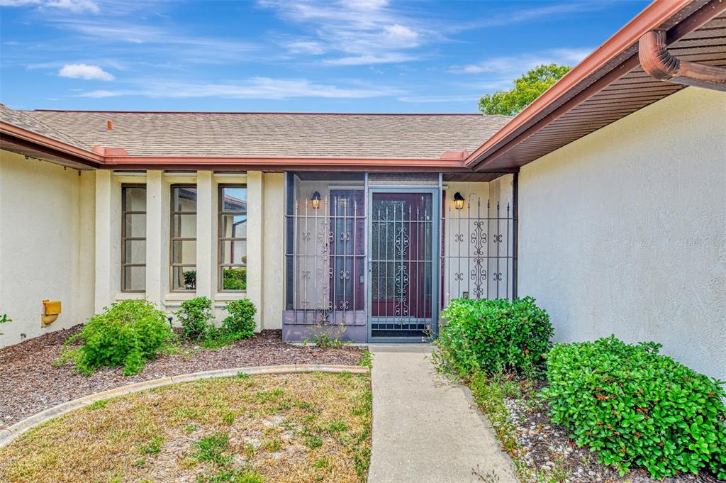 The exterior of a single-story house features a front entrance with a metal security gate — 5833 MADISON ROAD, VENICE, FL