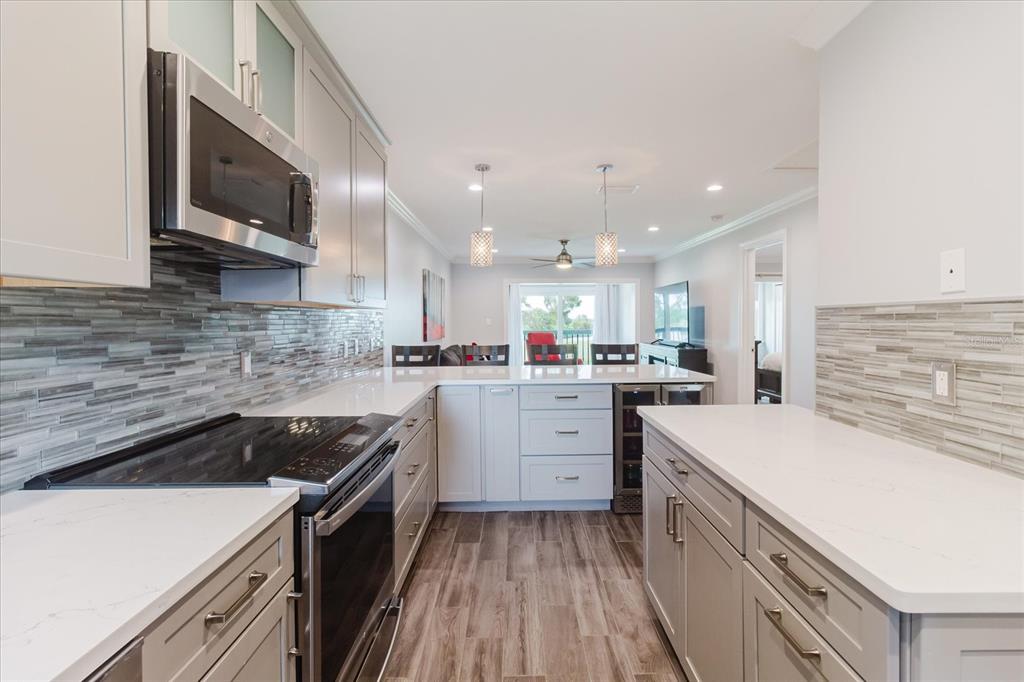 A modern kitchen features gray cabinets, white countertops, a tile backsplash, and stainless steel appliances — 2073 SKIMMER COURT W UNIT 222, CLEARWATER, FL