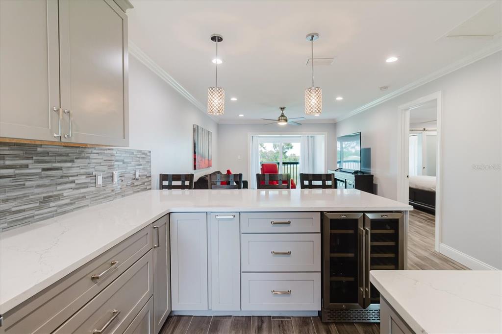 A kitchen features gray cabinets, white countertops, a tiled backsplash, and a built-in wine cooler — 2073 SKIMMER COURT W UNIT 222, CLEARWATER, FL