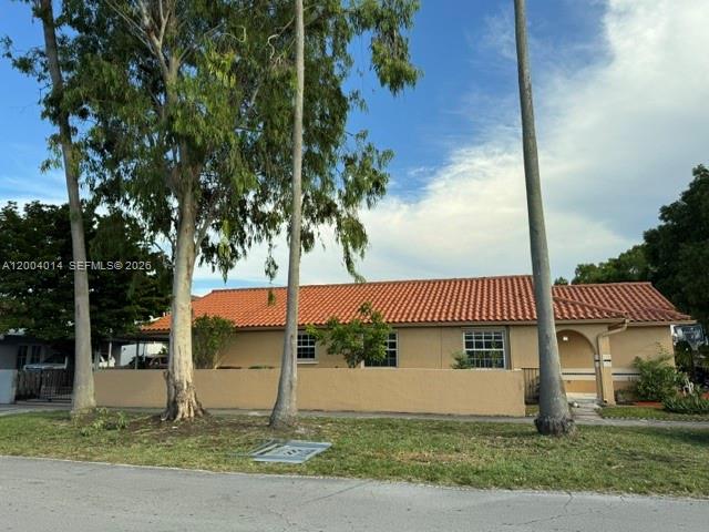 A single-story house with a terracotta tile roof stands behind a low tan wall — 7599 W 4th Ct, Hialeah FL 33014, HIALEAH, FL