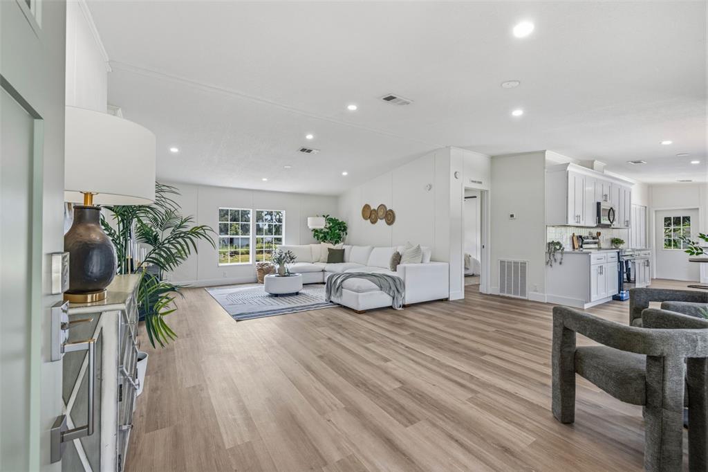 An open-concept living room and kitchen feature light wood flooring and white walls — 5005 SUGAR OAK LANE, DOVER, FL