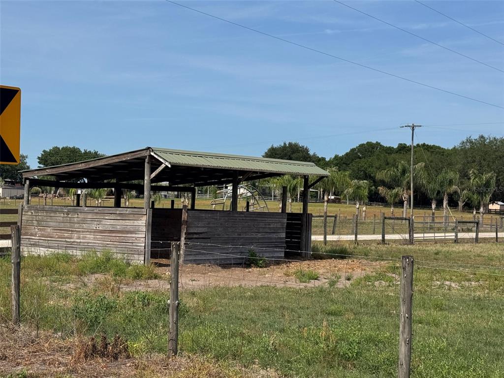 A wooden run-in shed stands in a grassy pasture enclosed by wire fencing — 807 CAMPBELL LANE, DE LEON SPRINGS, FL
