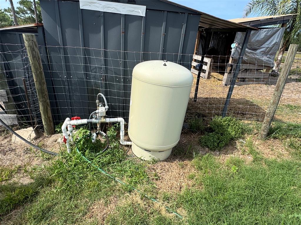 A beige well pressure tank sits outside next to a shed and wire fence — 807 CAMPBELL LANE, DE LEON SPRINGS, FL