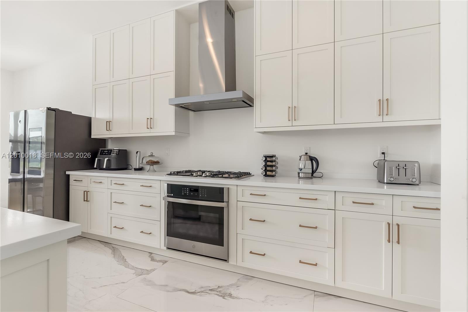 A modern kitchen features white shaker cabinets, stainless steel appliances, and marble-patterned tile flooring — 17197 Teton River Rd, Boca Raton FL 33496, BOCA RATON, FL