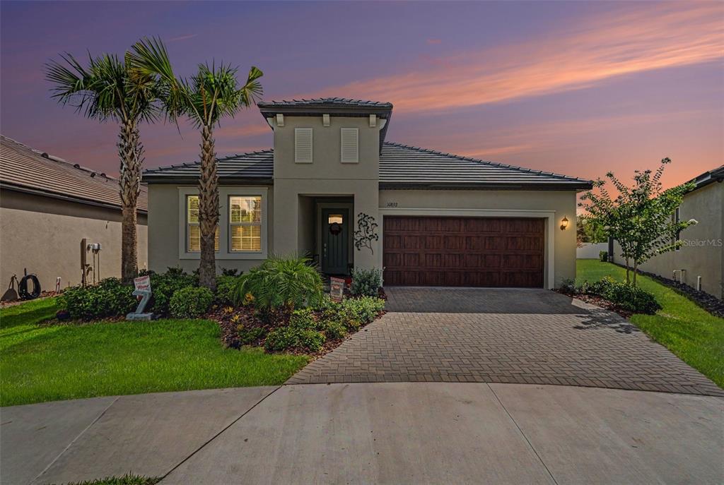 A single-story house with a paved driveway, two palm trees, and a dark garage door — 10892 IBIS BROOK COURT, LAND O LAKES, FL