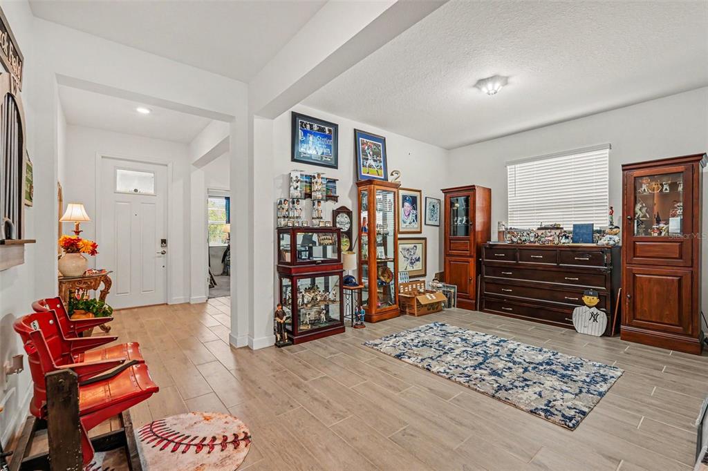A room with tile flooring, red stadium seats, and several glass display cabinets for collectibles — 10892 IBIS BROOK COURT, LAND O LAKES, FL