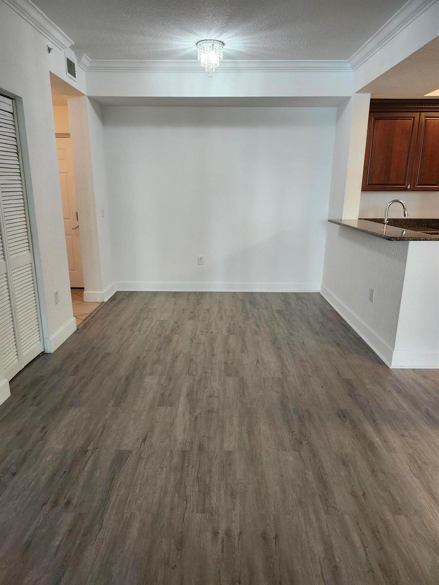 An empty dining area features wood-look flooring, white walls, and a crystal chandelier — 1660 Renaissance Commons Boulevard # 2122, Boynton Beach FL 33426, BOYNTON BEACH, FL
