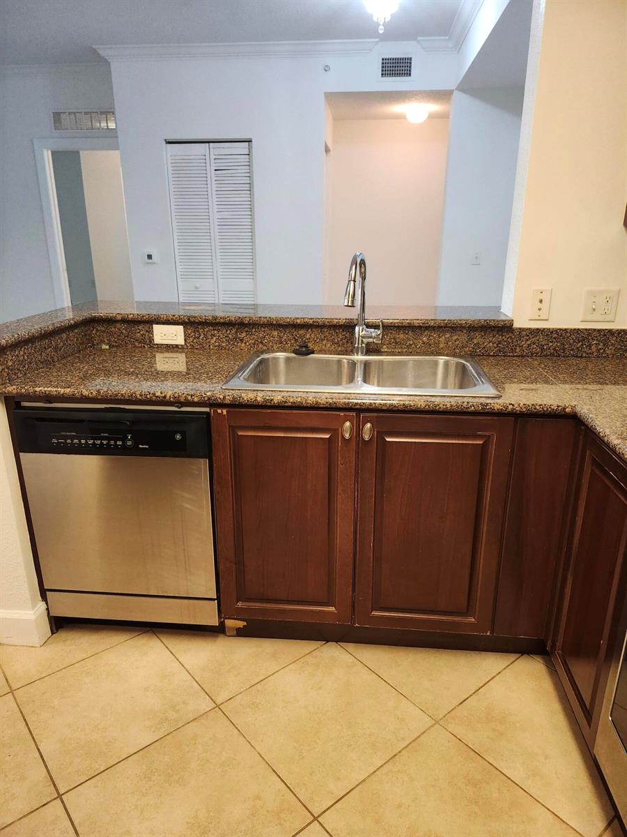 A kitchen features a stainless steel dishwasher, double sink, and brown granite countertops — 1660 Renaissance Commons Boulevard # 2122, Boynton Beach FL 33426, BOYNTON BEACH, FL