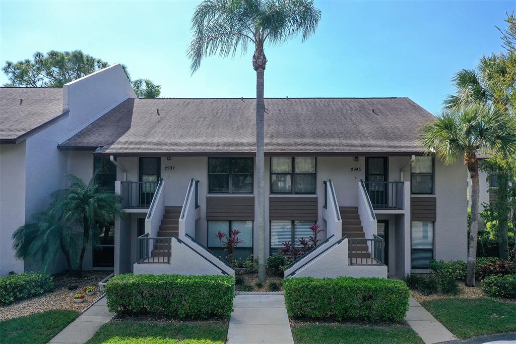 A two-story residential building features two exterior staircases leading to upper-level balconies — 2937 TAYWOOD MEADOWS UNIT 32, SARASOTA, FL