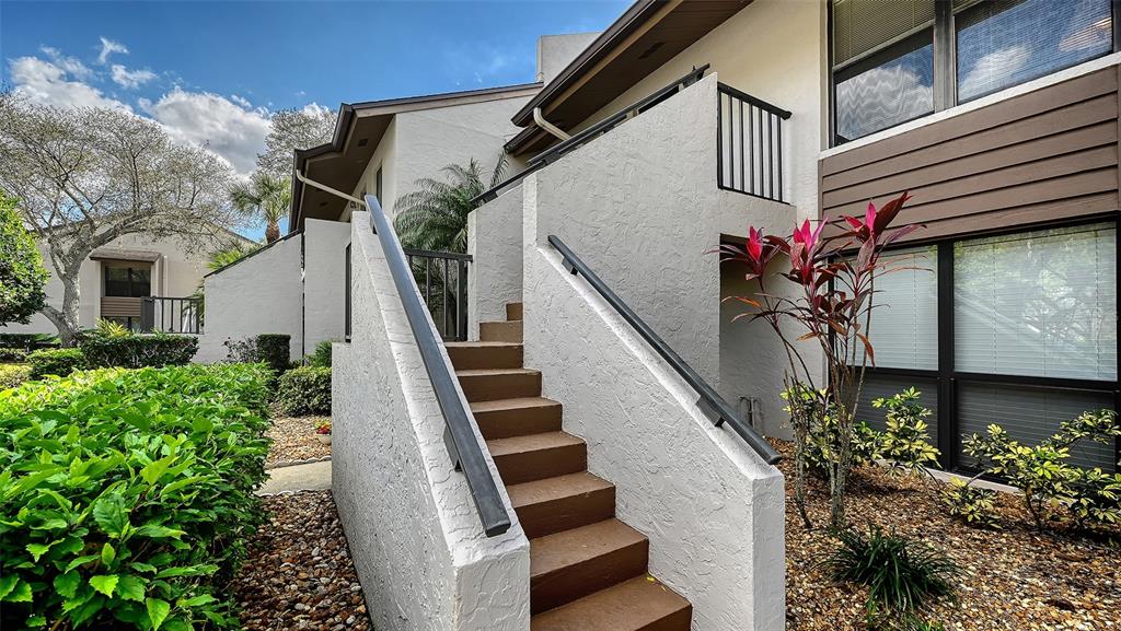 Exterior view of a building with a concrete staircase leading to an upper level — 2937 TAYWOOD MEADOWS UNIT 32, SARASOTA, FL