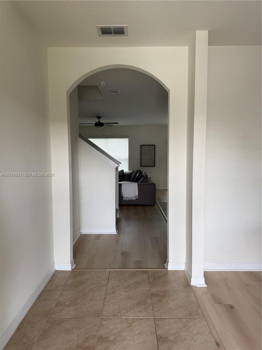 A tiled entryway leads through an arched doorway into a living area with wood flooring — 1630 Reddish Egret, Davenport FL 33897, DAVENPORT, FL
