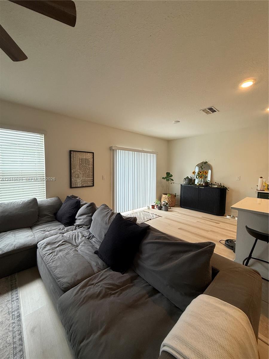A living room features a large gray sectional sofa, light wood floors, and sliding glass doors — 1630 Reddish Egret, Davenport FL 33897, DAVENPORT, FL